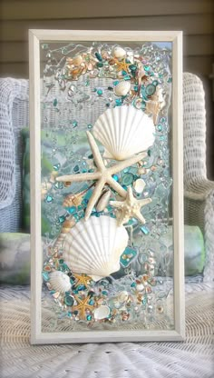 two seashells and starfish are on the beach in this framed glass art piece