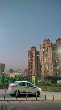 a white car driving past tall buildings at night