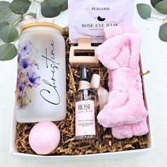 a pink gift box with personal care items in it and some flowers on the table