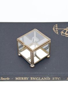 a glass and metal box on top of a book with the words merry england etc