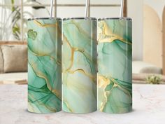 three green and gold marbled tumbles sitting on a table next to a couch