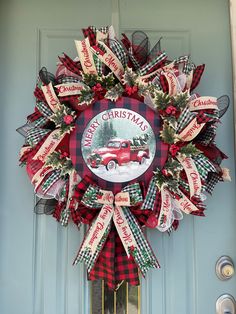 a christmas wreath on the front door of a house with red and green plaid ribbon