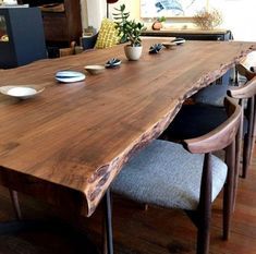 a large wooden table with two chairs and a vase on the top, in a living room