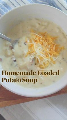 a white bowl filled with soup and cheese on top of a cutting board next to some crackers