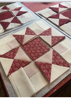 several red and white quilts are laid out on a table with one block missing