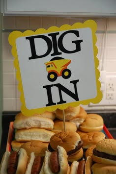 a pile of hot dogs sitting on top of buns next to a sign that says dig in