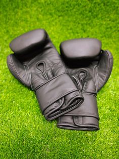 a pair of black leather gloves laying on top of green grass