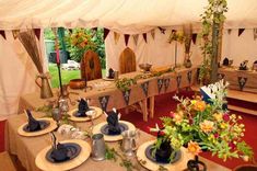 the tables are set up for an outdoor event with flowers in vases and napkins on them