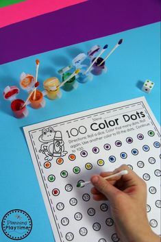 a hand is writing on a color dot activity sheet