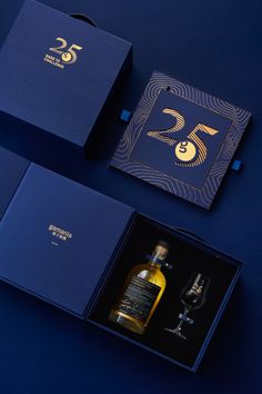 two bottles of whisky in blue boxes next to each other on a blue surface with gold lettering