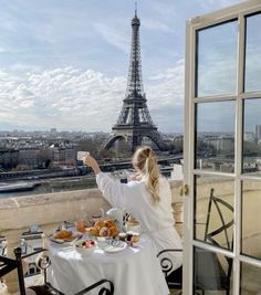 a woman sitting at a table with food in front of the eiffel tower