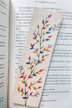 the bookmark is decorated with colorful flowers and leaves on it's side, next to an open book