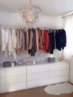 a closet with clothes hanging on the wall and a chandelier in the corner