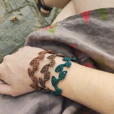 a close up of a person's arm wearing bracelets with leaves on them