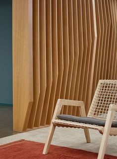 a chair sitting on top of a red rug in front of a wooden slatted wall