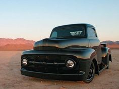 an old black truck is parked in the desert