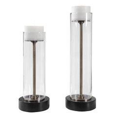 two glass and metal candlesticks sitting next to each other on a white background