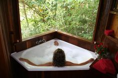 a woman sitting in a bathtub looking out the window