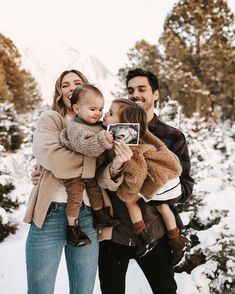 a man, woman and child are standing in the snow with their arms around each other