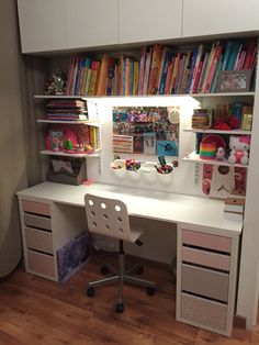 a white desk topped with lots of books next to a book shelf filled with children's books