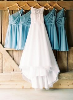 three bridesmaid dresses hanging on a rack in front of a barn door with wooden slats