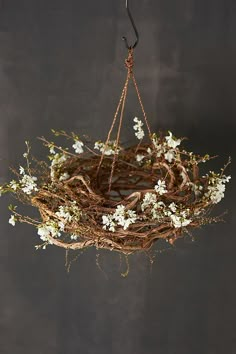 a wreath hanging from the ceiling with white flowers on it and an iron hook in the middle