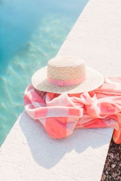 a hat and blanket sitting on the edge of a pool