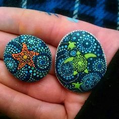 two painted rocks in the palm of someone's hand, one has an orange star on it