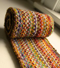 a multicolored knitted tie sitting on top of a white table next to a window