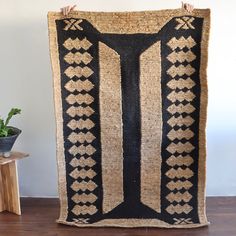 a large black and tan rug on top of a wooden table next to a potted plant