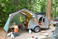 a man standing in front of a camper trailer with its door open and cooking food