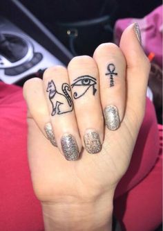 two fingers with tattoos on them, one has an egyptian symbol and the other has an eye