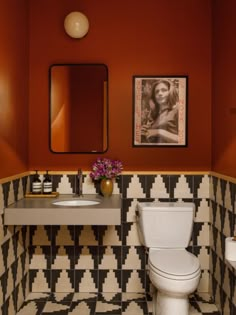 a white toilet sitting next to a sink in a bathroom under a framed picture on the wall