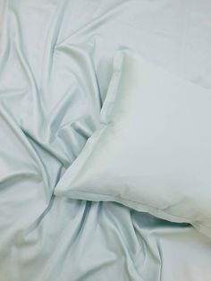 an unmade bed with white sheets and pillows