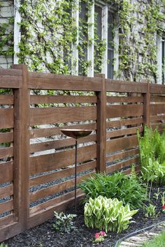 a wooden fence surrounded by plants and flowers