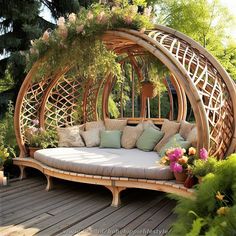 an outdoor day bed with pillows and flowers on the ground in front of some trees