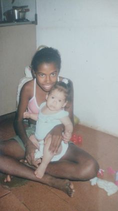 a woman sitting on the floor holding a baby