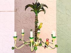 a chandelier with two parrots sitting on it's arms next to a pink wall