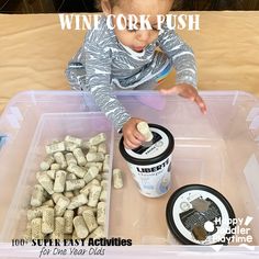 a toddler playing with wine corks in a plastic container on top of a table