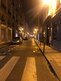 an empty street at night with cars parked on the side