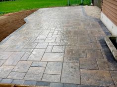 an outdoor patio with brick pavers and grass in the back yard, next to a house