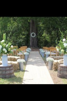 an outdoor ceremony setup with chairs and flowers in buckets at the end of the aisle