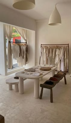 the inside of a clothing store with clothes hanging on racks and two benches in front of them