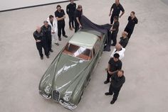 a group of people standing around a green car