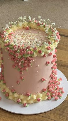 a pink birthday cake decorated with flowers on a plate