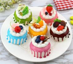 there are many small cakes on the plate with icing and fruit toppings in them