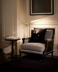 a living room with a chair, table and lamp on it's side wall