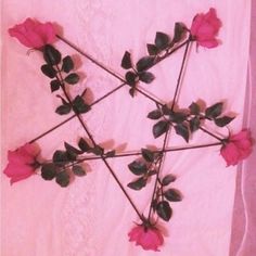 four red roses arranged in the shape of a star on a pink sheet with lace