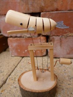 a small wooden object sitting on top of a piece of wood next to a brick wall