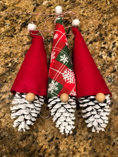 three christmas cones with snowflakes on them sitting on a granite counter next to pine cones